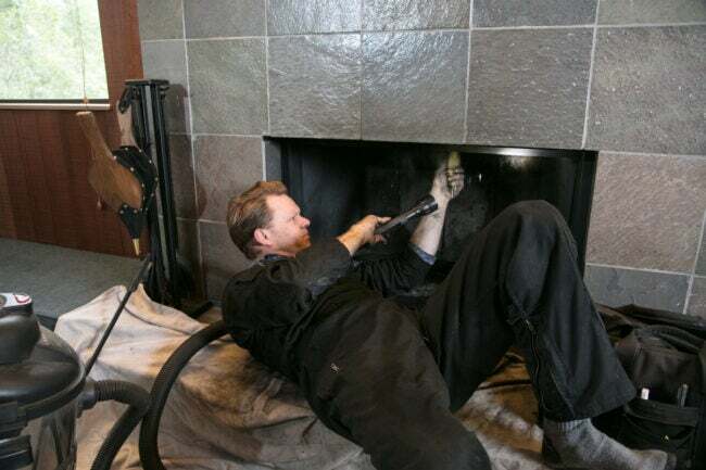 homme allongé sur le dos sur le sol et nettoyant la cheminée et la cheminée