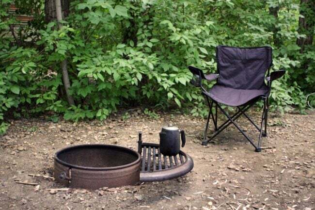Cadeira de acampamento ao lado de uma fogueira vazia e apagada