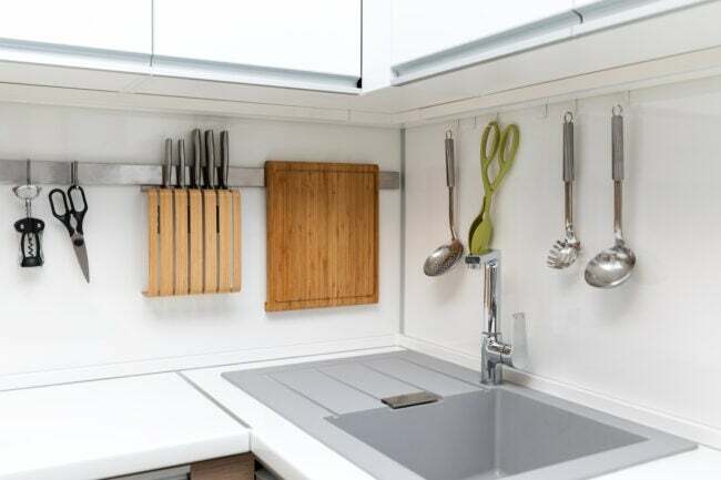 iStock-905477904 необхідно виконати лютневі проекти. Білий глянсовий дизайн інтер’єру кухні з висячим посудом.
