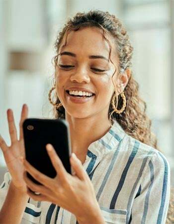 Una mujer sonríe mientras mira su teléfono. 