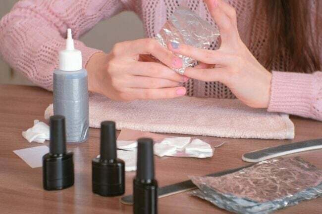 Mujer usando varias herramientas para el cuidado de las uñas