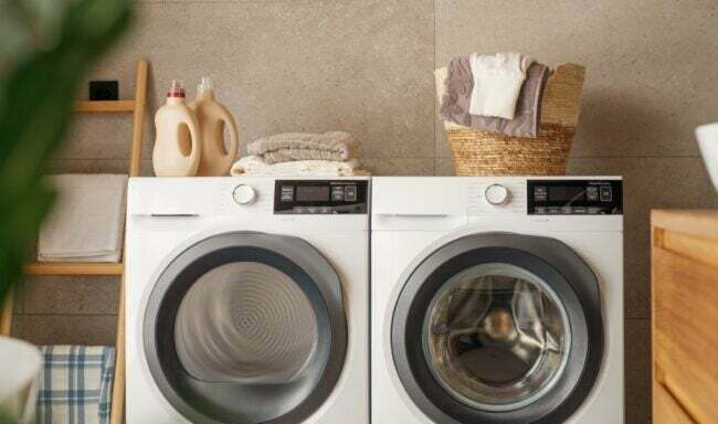 Weiße Waschmaschine und Trockner mit Wäschekorb und Seife an der Spitze