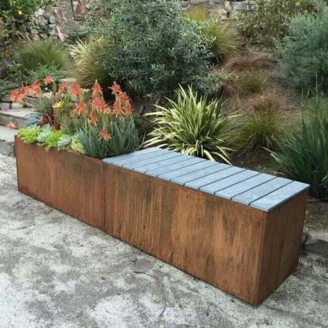 Un banc de jardin en bois qui a une jardinière intégrée avec des plantes colorées.