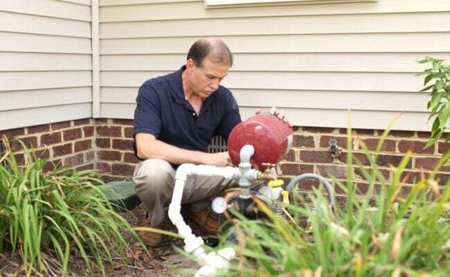 Un uomo che controlla la pompa del pozzo all'esterno di una casa residenziale.