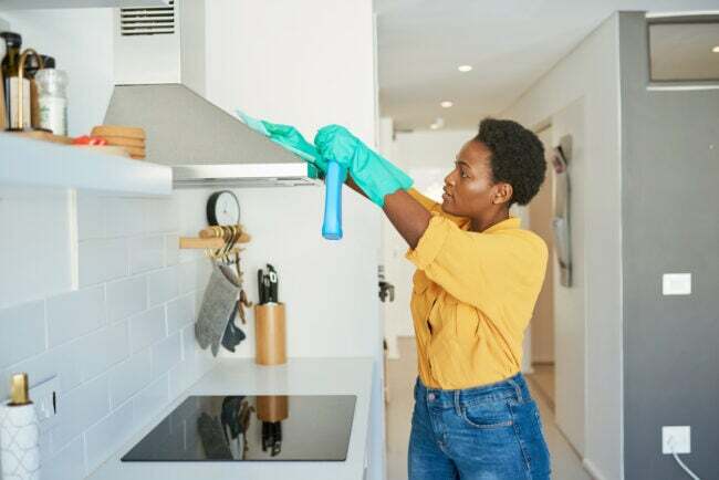 امرأة تنظف شفاط المطبخ في مطبخ أبيض