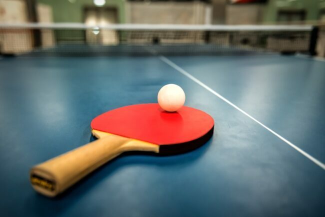 Ping-pong sur raquette rouge, assis sur une table de ping-pong