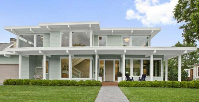 Moderný dom je vymaľovaný v bledomodrej farbe s bielym lemovaním.