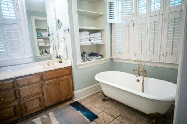 Головна ванна кімната у великому будинку зі склепінчастою стелею та дерев’яними шафами