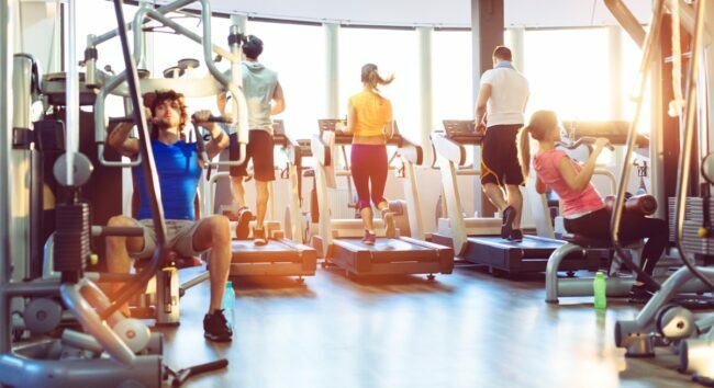 الأشخاص الذين يمارسون التمارين الرياضية على المطاحن وآلات الوزن في صالة الألعاب الرياضية