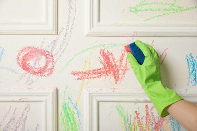 стирание красочных рисунков карандашом со стены в зеленых перчатках губкой