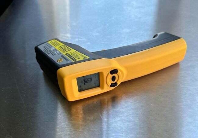 Жълт и черен ThermoWorks IR пистолет отстрани върху плот от неръждаема стомана