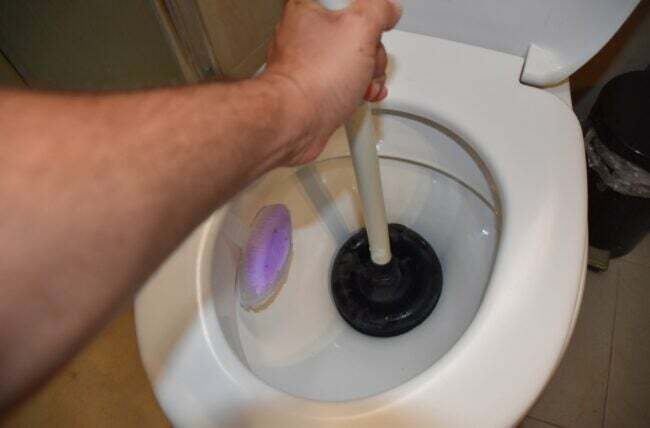 Mão usando a imersão do vaso sanitário