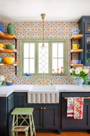Šarena narančasta, plava i bijela kuhinjska pozadina naglašena svijetlozelenim prozorom i tamnoplavim elementima