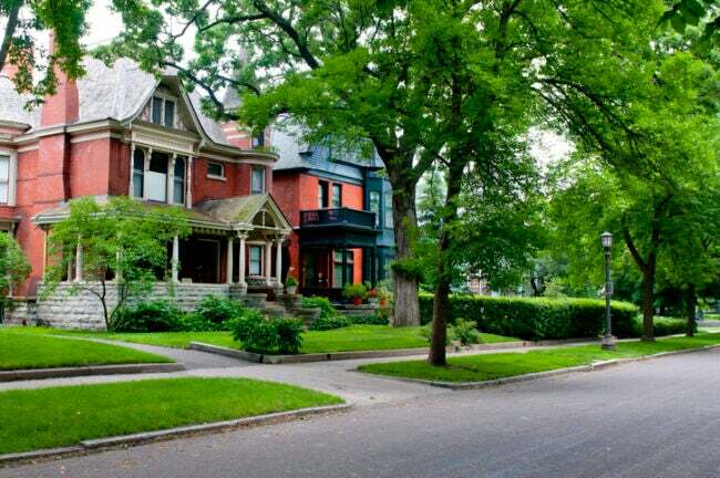 kebenaran tentang membeli dan tinggal di rumah tua bergaya victorian depan rumah merah dengan pohon-pohon besar