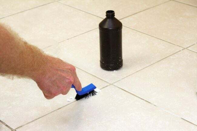 ręczne szorowanie płytek za pomocą narzędzia do czyszczenia, z butelką nadtlenku wodoru