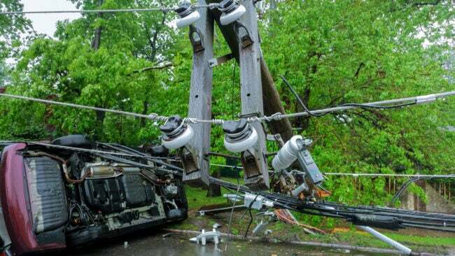 I pali dell'elettricità cadono a causa delle tempeste. auto danneggiata