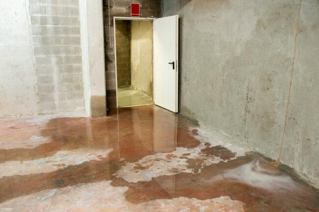 Daño por agua en el sótano causado por reflujo de alcantarillado debido a drenaje sanitario obstruido