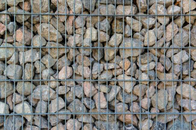 გაბიონის საყრდენი კედლის ახლო ხედი, რომელიც დამზადებულია რიპრაპისგან და ლითონის მავთულის ჩარჩოსგან
