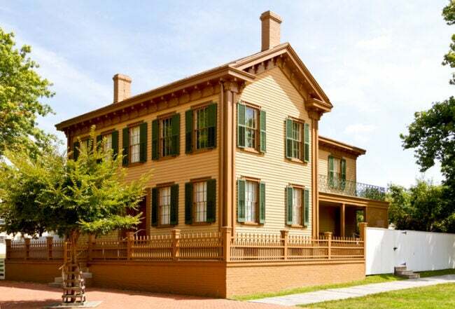 et-gresk-revivial-hjem-med-solbrun-utvendig-og-mørkegrønne-skodder-sittende-på-en-hjørne-tomt-med-et-tre-er-Abraham-Lincolns-hjem