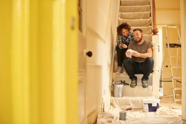 زوجان يجلسان على الدرج في منتصف عملية إصلاح المنزل