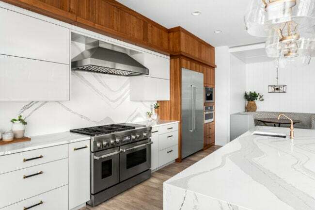 Cozinha ampla com bancada de quartzo branco, ilha de cozinha de quartzo e detalhes em madeira