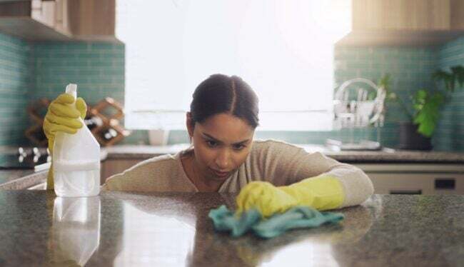 청소하는 동안 화강암 조리대를 자세히 보는 여성