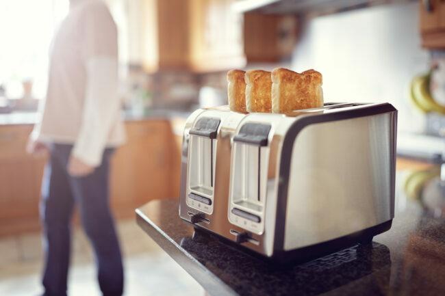 Sabahın erken saatlerinde kızarmış ekmek, mutfaktaki adam gün doğumunda kahvaltı için tost hazırlıyor.