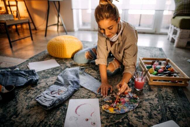 iStock-1354236427 kaunistab käsitööga noor naine, kes maalib ja teeb teksariidest kangakunsti.