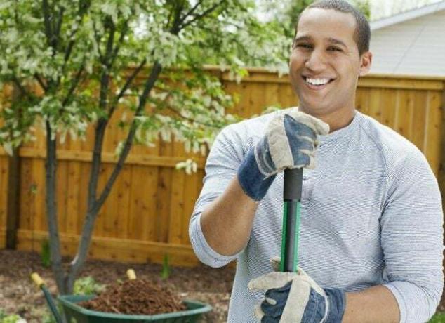 uomo che indossa guanti da giardino facendo yardwork