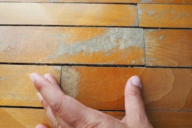 Tampilan tangan dari dekat merasakan papan lantai kayu keras.