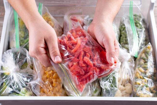 Pimentões vermelhos congelados. Legumes congelados em um saco plástico na geladeira