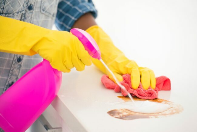 rózsaszín spray-palack, amely egy foltot céloz meg a konyhaasztalon 