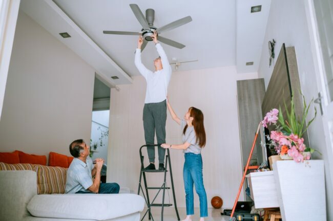 Homem ajudando a família a mudar a direção do ventilador de teto na escada.