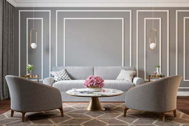 Obývacia izba so sivými stenami, bielym lemovaním a zlatými prvkami