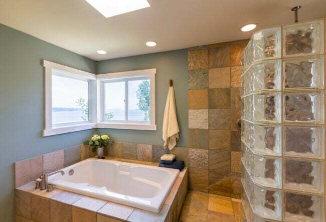 ジャグジー浴槽とガラスブロック窓の壁を備えた素敵なモダンなバスルーム