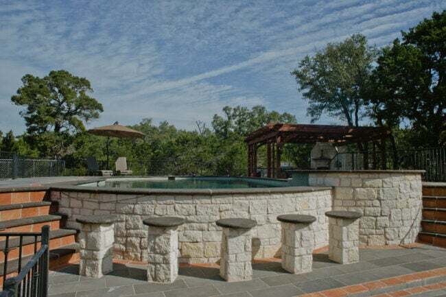 Nadzemní bazén s kamennou bazénovou terasou a dřevěnou pergolou