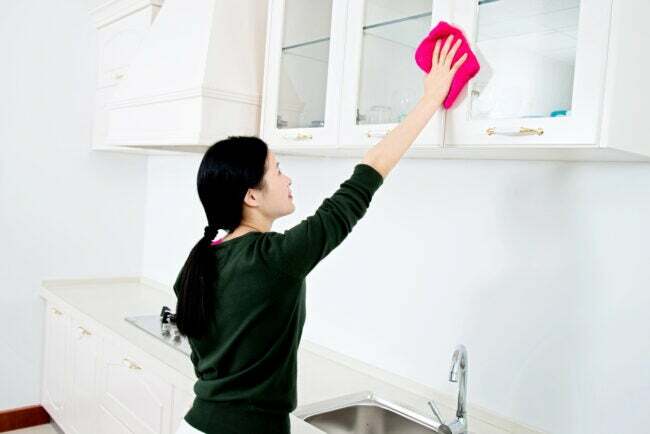 mujer asiática limpiando gabinetes de cocina