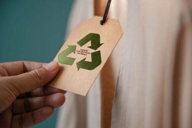 Een persoon die een prijskaartje vasthoudt met de woorden 'gemaakt van 100 procent gerecyclede materialen' erop.