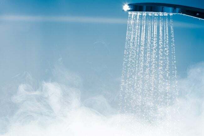 Água saindo do chuveiro com vapor.