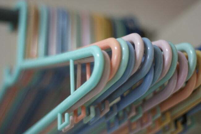 Pastellfarbene Kleiderbügel aus Kunststoff hängen im Schrank 