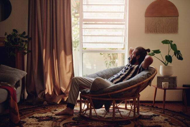 Jovem barbudo descansando em uma sala de estar iluminada por luz natural