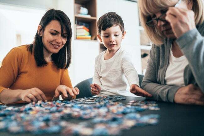 Familie die een puzzel samenstelt op een zwart tafelblad