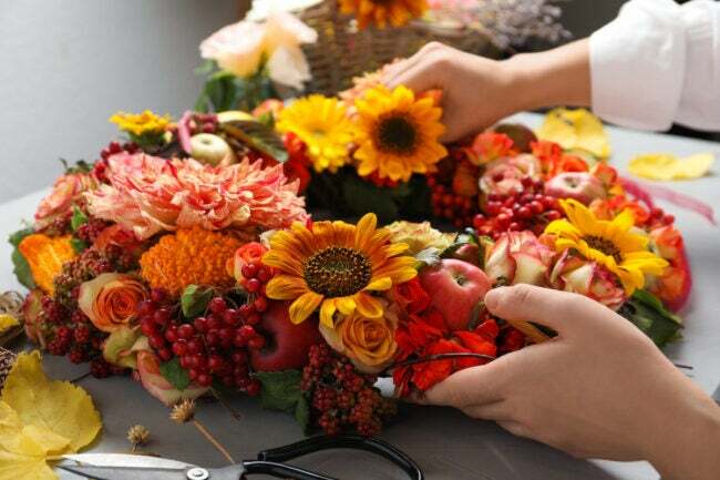uusi vuosi uusi taito itse kukkakauppias tekee seppelettä kukilla ja hedelmillä