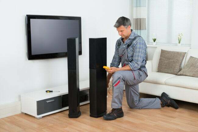 Teknisi memeriksa speaker TV dengan multimeter di rumah