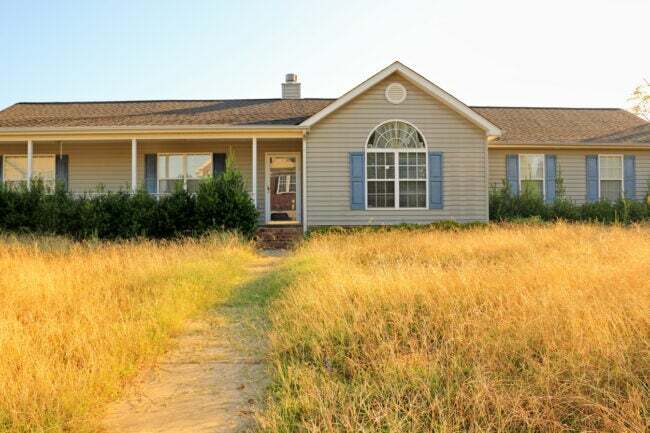 ranch stílusú ház ápolatlan udvarral, száraz, sárga benőtt pázsittal