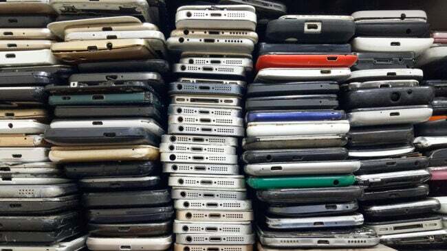 विभिन्न ब्रांडों और रंगों के ट्रेड-इन स्मार्टफ़ोन की लंबी कतारें। 