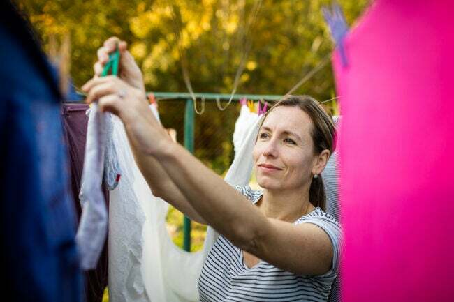 ženska obeša oblačila na vrvico za perilo zunaj, da pomaga odstraniti statično oprijem