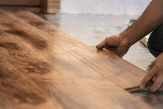 Detail člověka, kterým se stanoví dřevěná podlahová prkna. 
