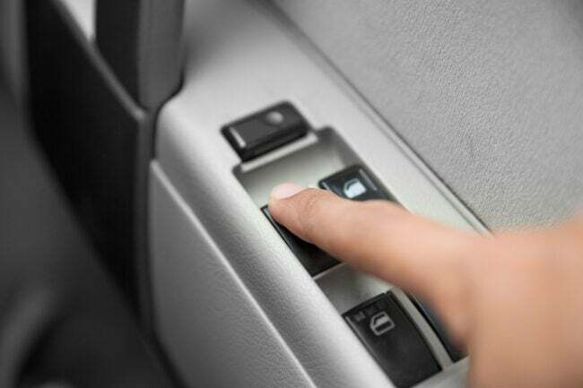 車のウィンドウコントロールのボタンを押す指の接写
