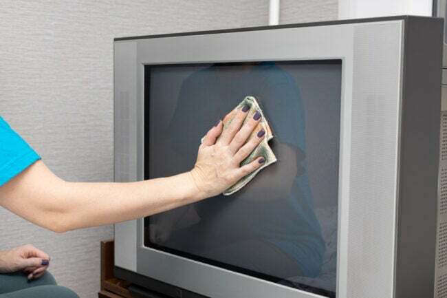 يد تنظف شريط سينمائي لتلفزيون CRT بشاشة مسطحة بقطعة قماش